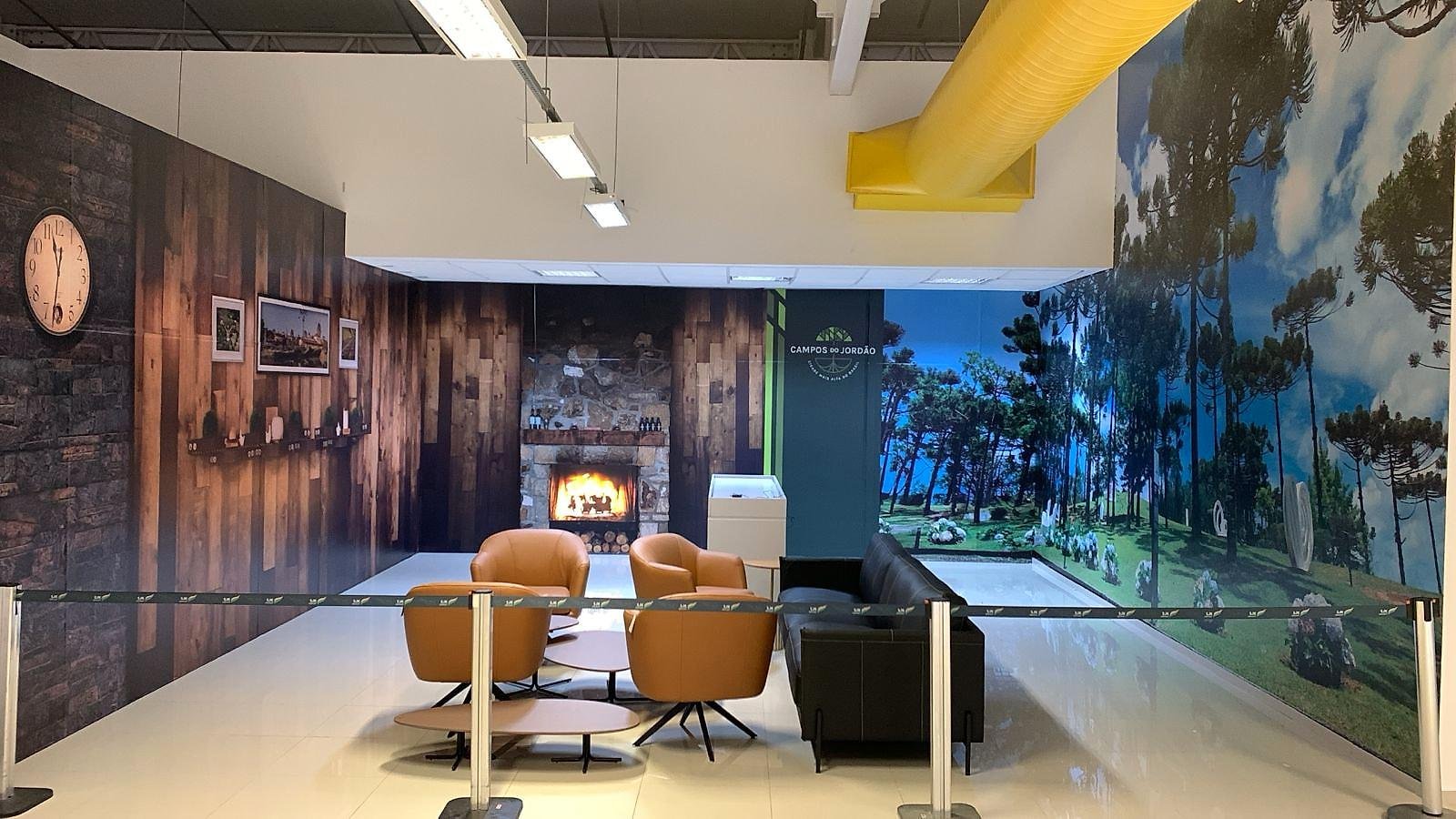 Espaço Campos do Jordão no Aeroporto Mall, com painéis de parede de madeira, lareira e pinheiros