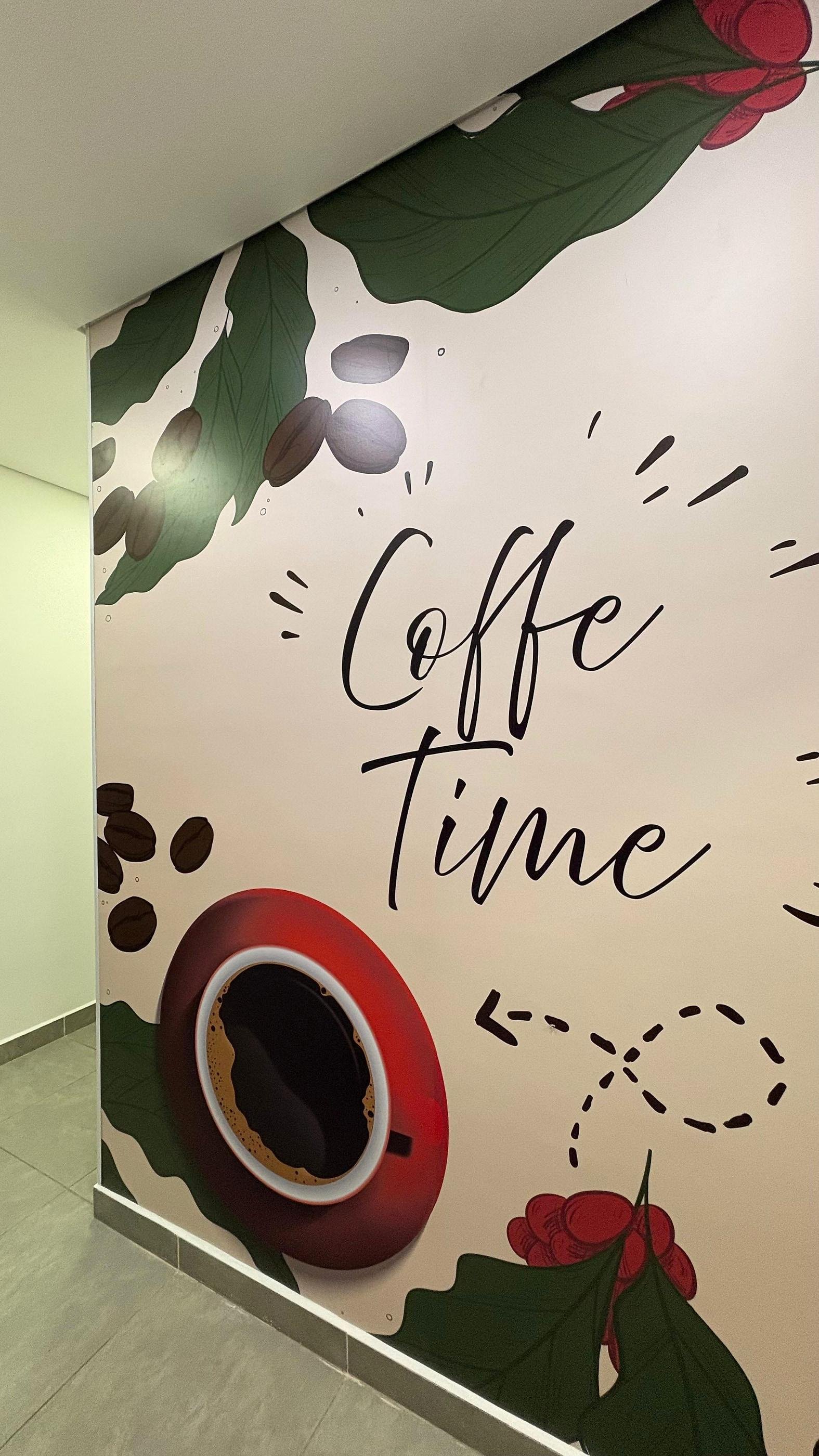 Parede adesivada com a arte "Coffe Time", xícara de café e folhas