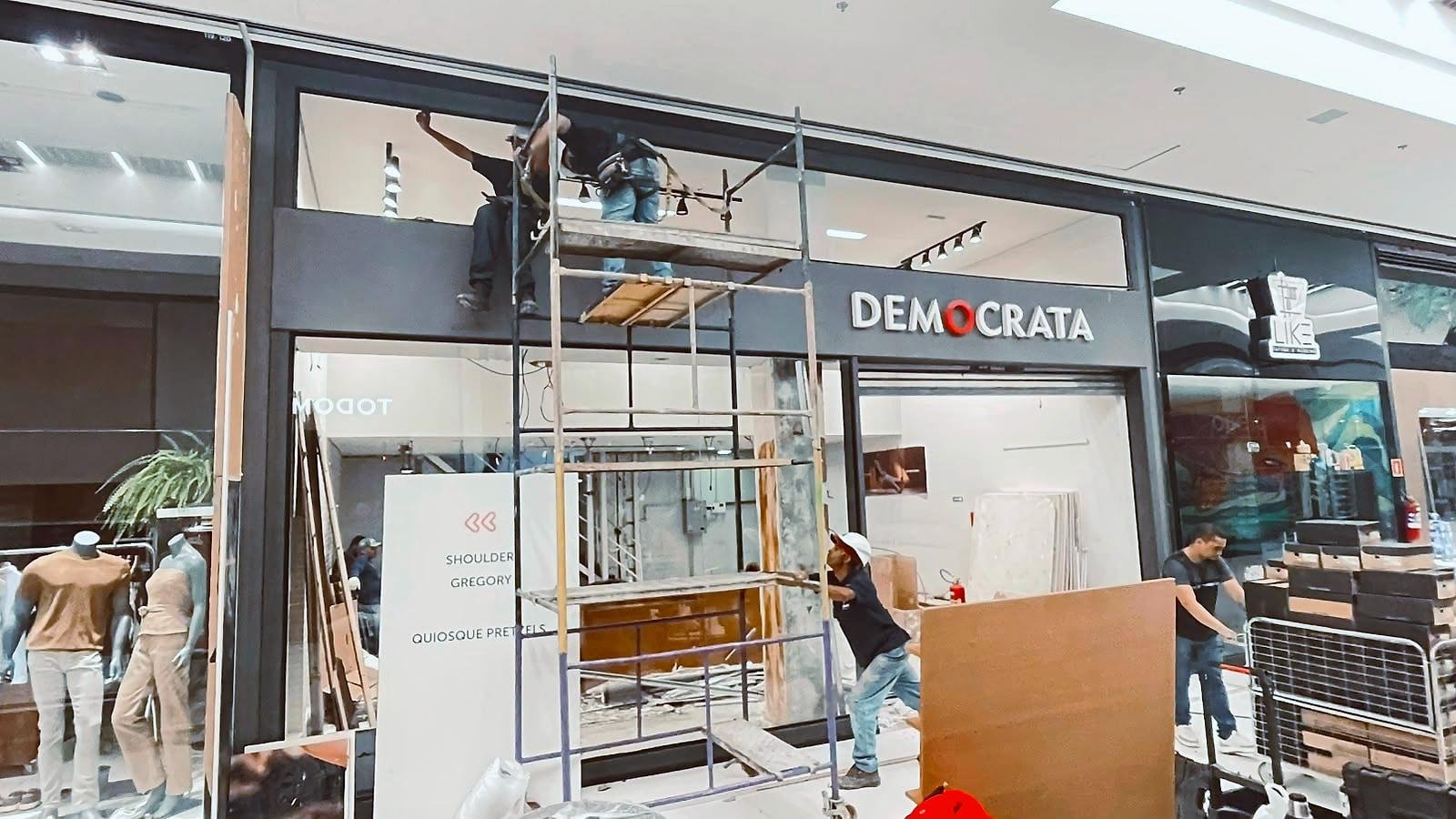 Equipe da Swan montando o tapume da Democrata no Mogi Shopping, com andaime em frente à loja